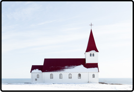 Small white church covered in snow with a burgundy roof against a white sky